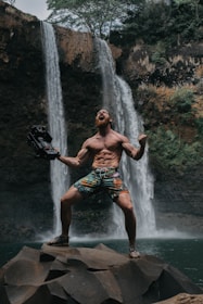 topless man screaming on top of rocks on waterfalls