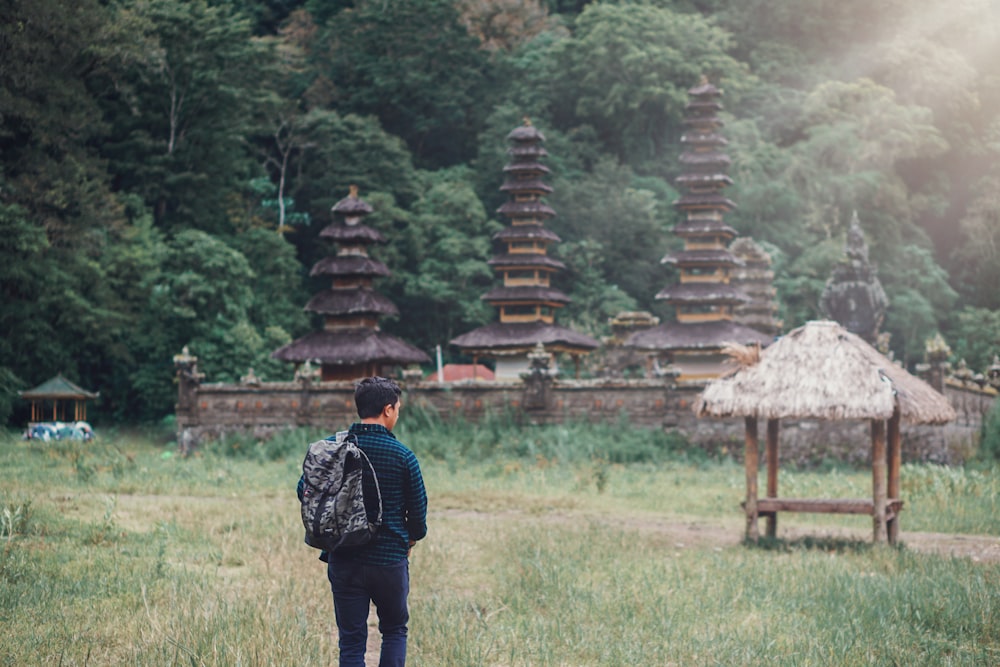 man walking on field near nipa hut