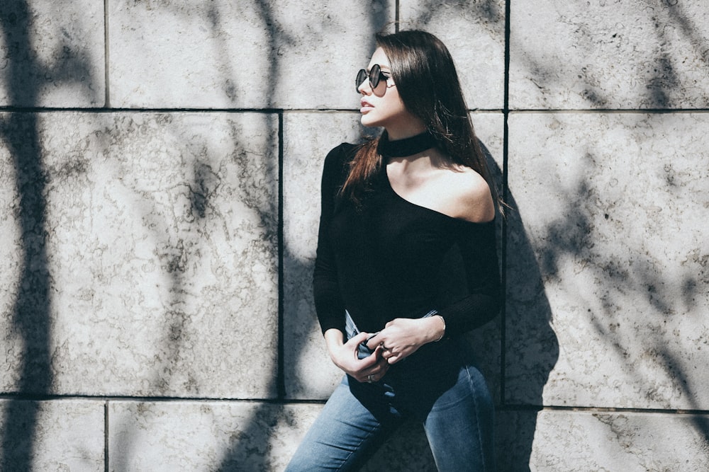 woman wearing black halter one-shoulder long-sleeved shirt and blue denim bottoms outfit during daytime