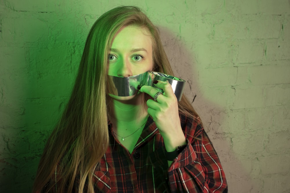 woman placing duct tape on her mouth