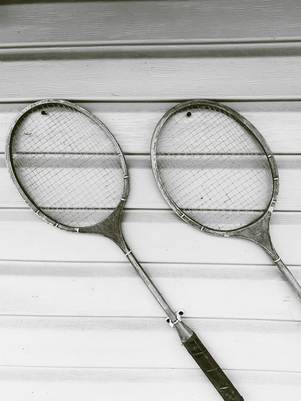 two gray badminton rackets on white wooden surface