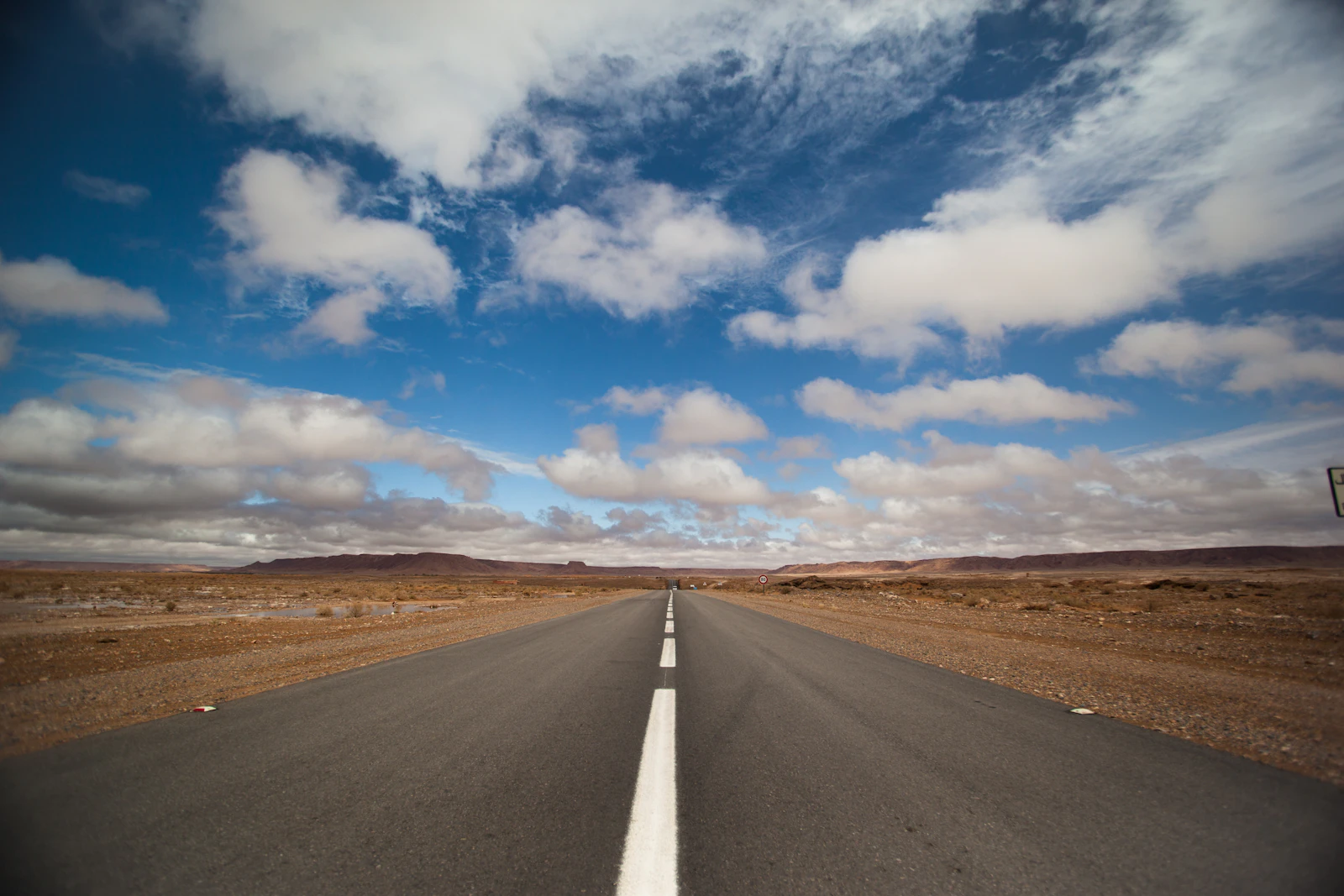 Longue route droite dans le sud du Maroc sous un ciel bleu