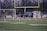 A young athlete practicing on a sports field with a coach providing guidance.
