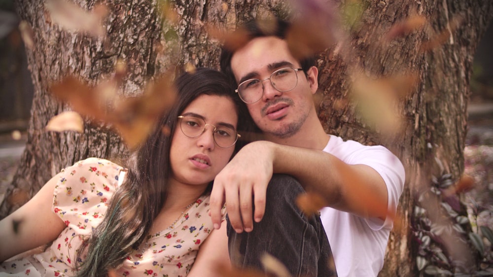 man and woman leaning on tree