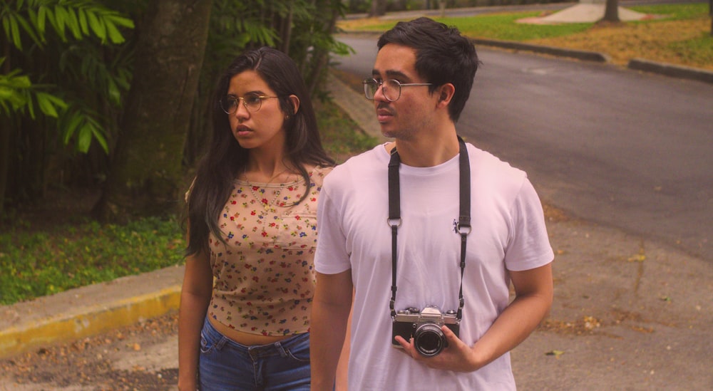 man and woman standing near trees and road