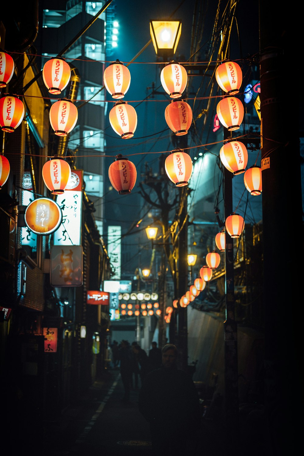 people walking pass under lighted lanterns