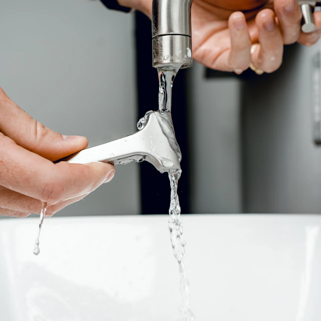 A silver faucet running over a basin