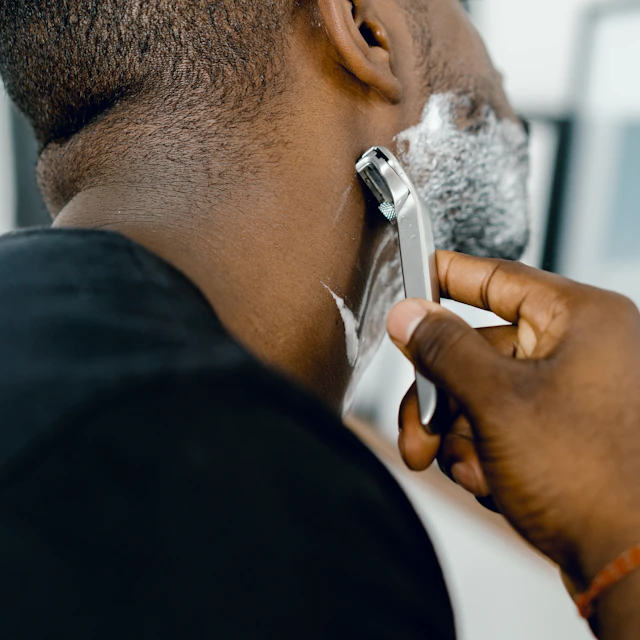A man shaving his face in front of a mirror