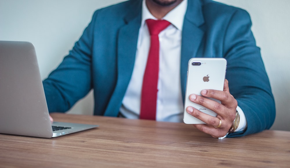 man sitting beside table holding silver iPhone 7 Plus