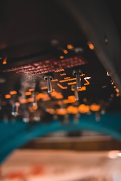 Close-up view of an aircraft cockpit panel featuring illuminated switches and circuit indicators. The background is blurred, emphasizing a warm glow from the lights.