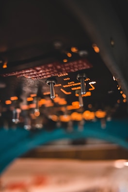 A close-up of a high-tech fighter jet cockpit illuminated by soft instrument lights at dusk.