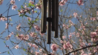 A colorful garden wind chime gently swaying in the breeze against a bright blue sky