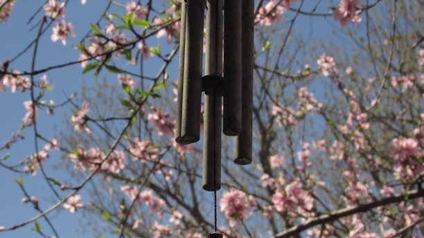 Close-up of colorful garden wind chimes gently swaying in a soft breeze against a bright blue sky.