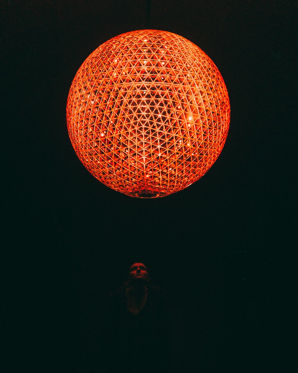 person looking at orange lighted ball on ceiling