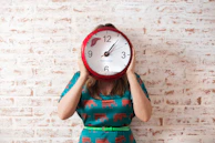 woman covering face using wall clock