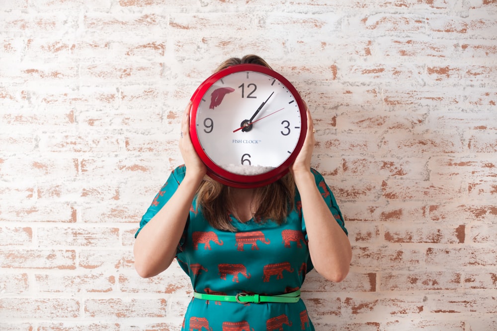 mujer cubriendo la cara con un reloj de pared