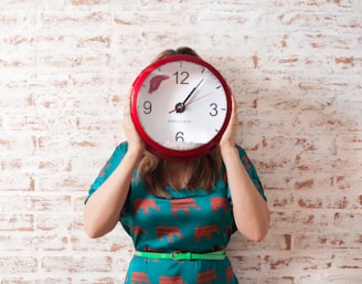 woman covering face using wall clock