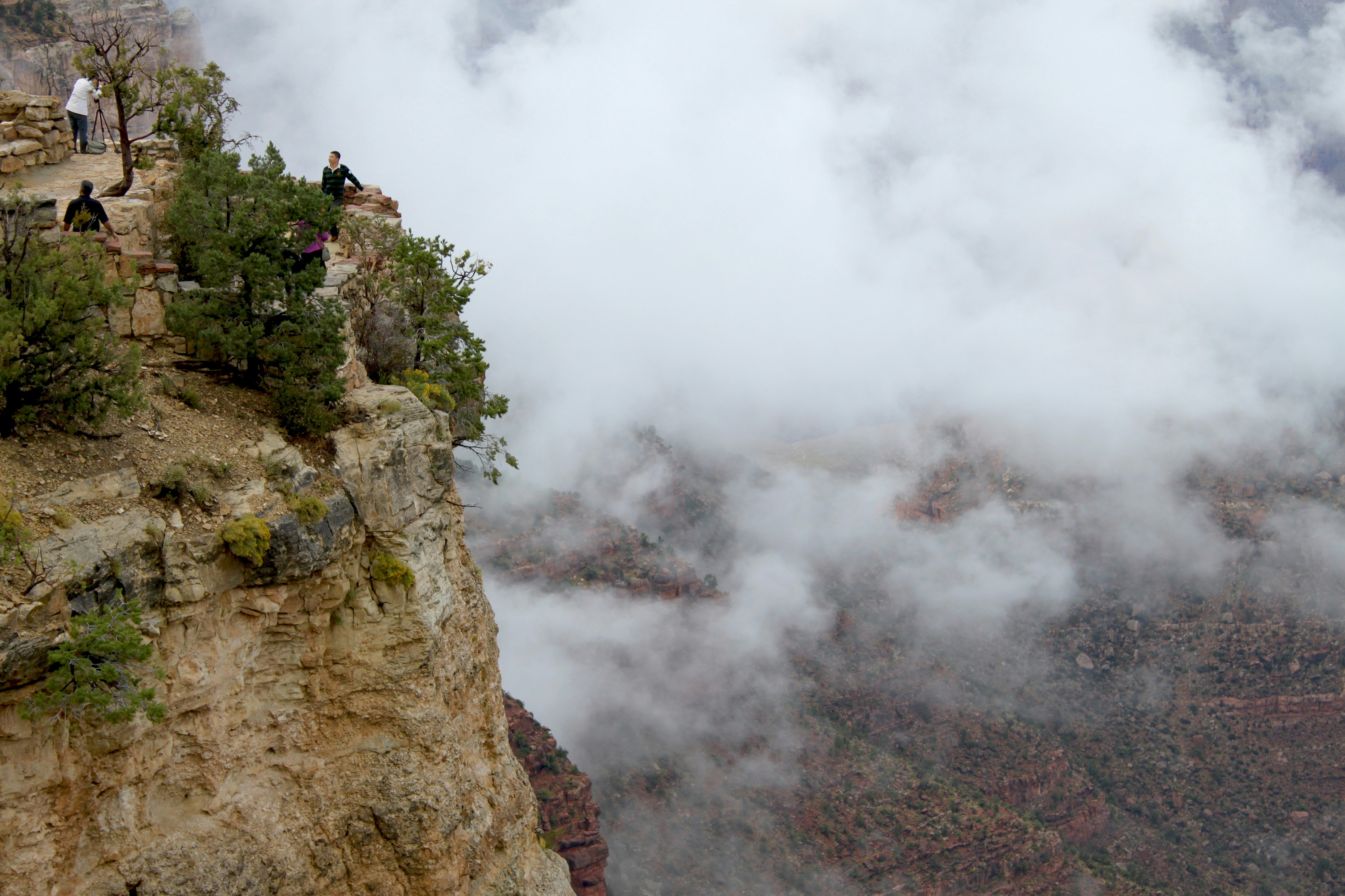 people standing on edge of mountain during daytime