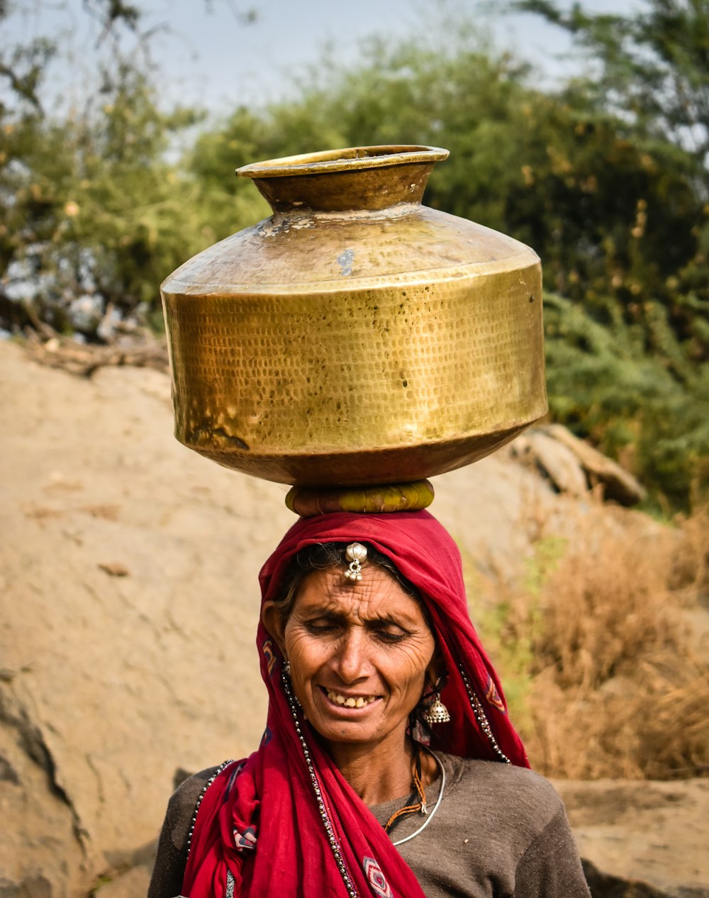 woman carrying gold jar on head