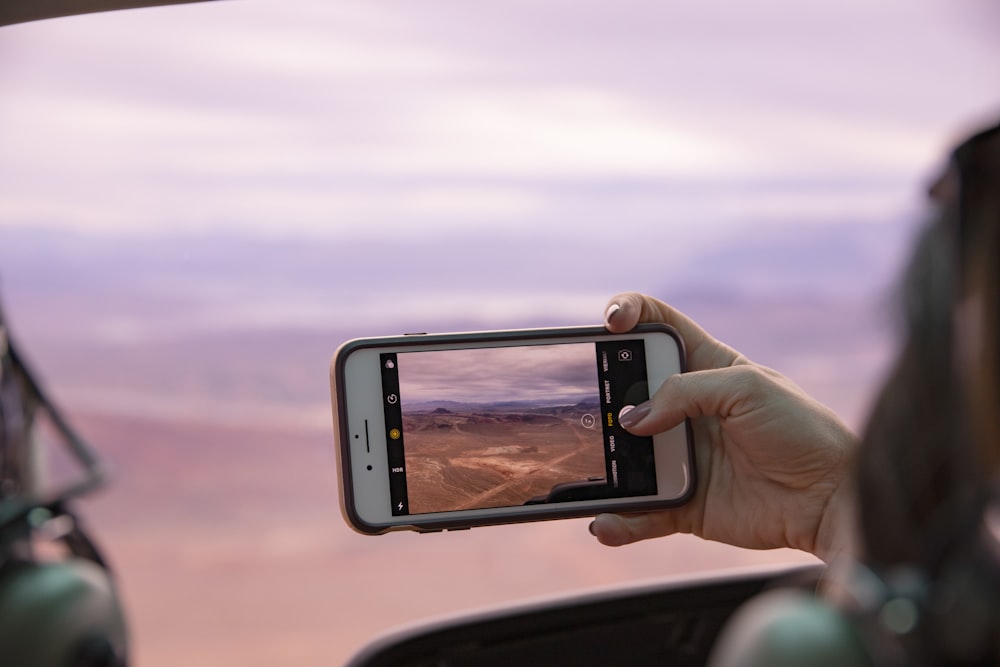 person taking photo of brown field