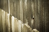 Weathered wooden fence panels with visible texture and natural aging, featuring a rustic and rugged appearance.