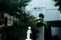 A tiny, detailed sculpture of a 1980s abstract figure on a minimalist pedestal.