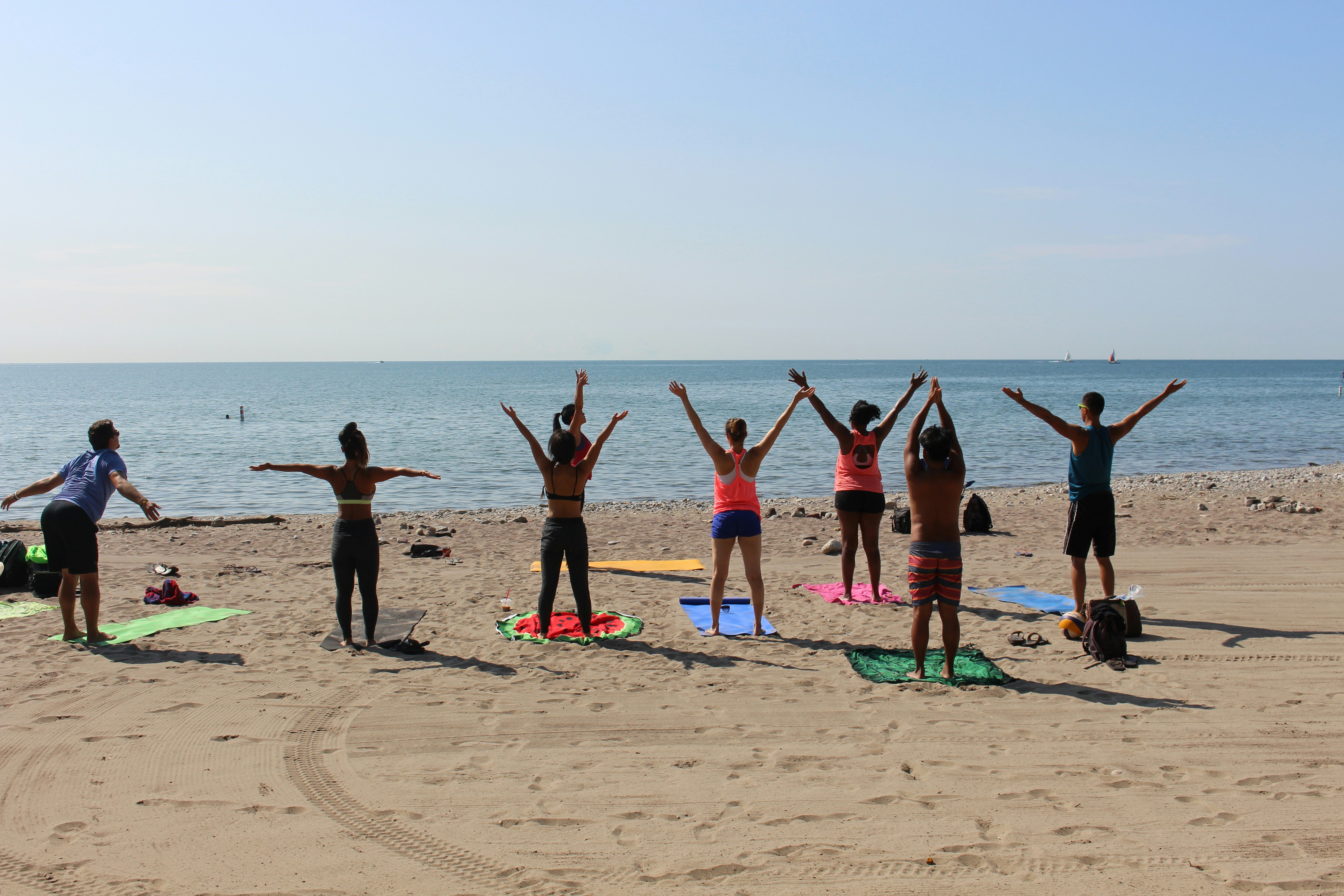 Yoga group on beach at sunrise doing poses together with ocean in background