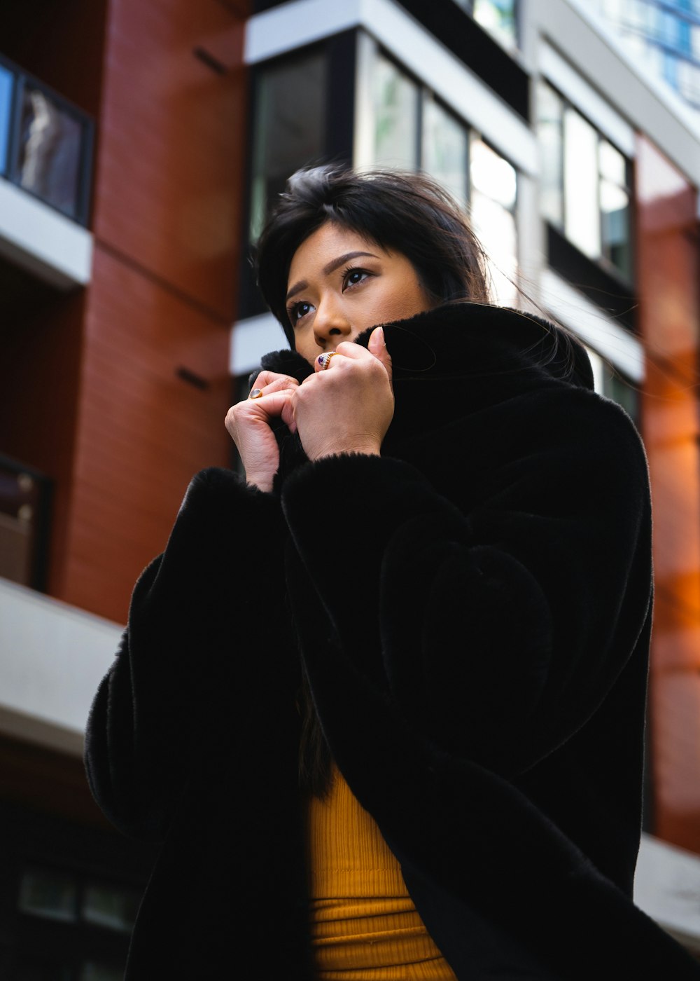 woman standing near brown building holding her jacket