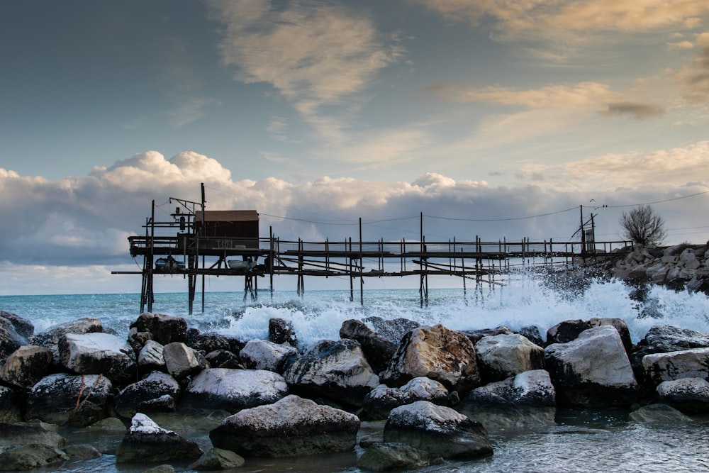 brown wooden dock on rocky beach