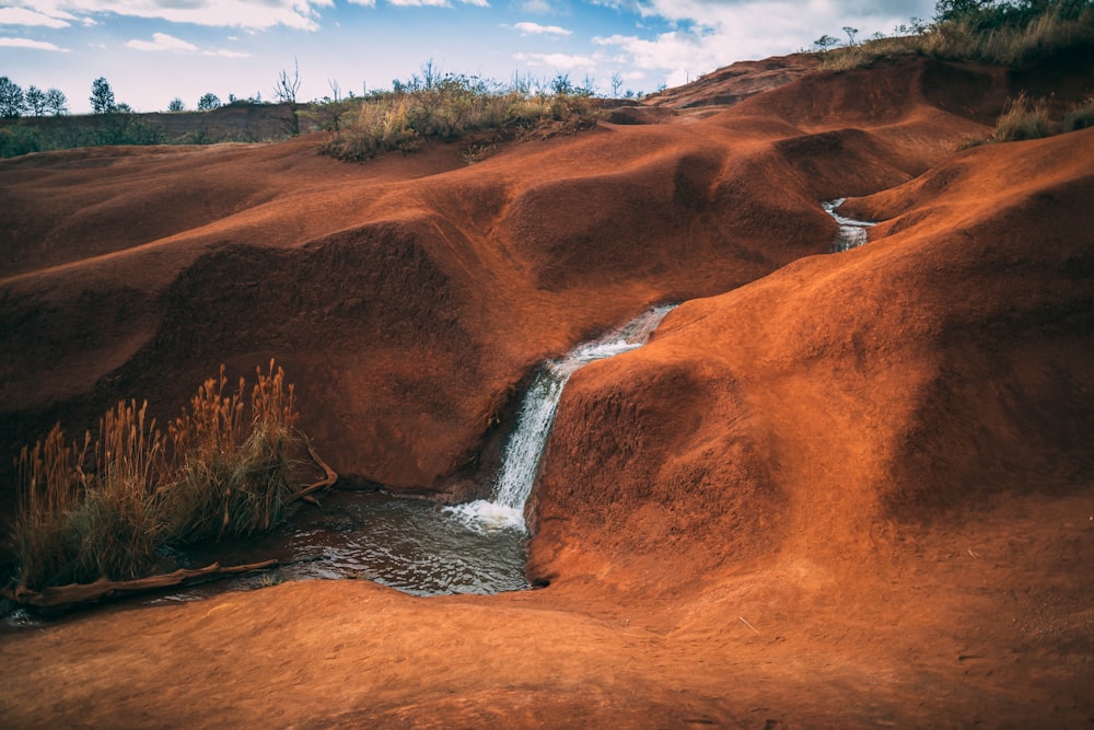 water flowing on brown hill