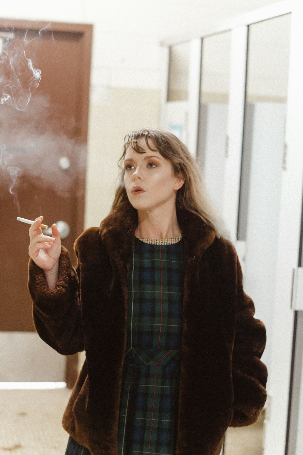 woman smoking by glass hallway