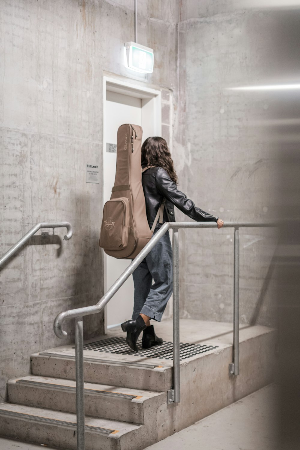 woman carrying brown gig bag standing near closed door