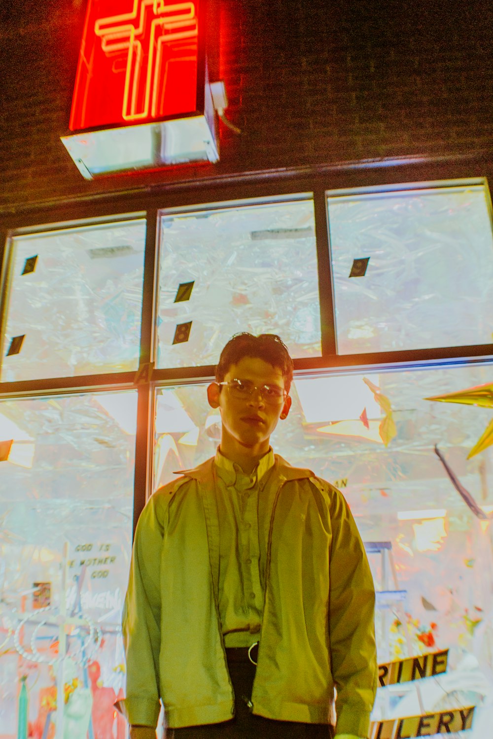 man standing below red lighted store sign