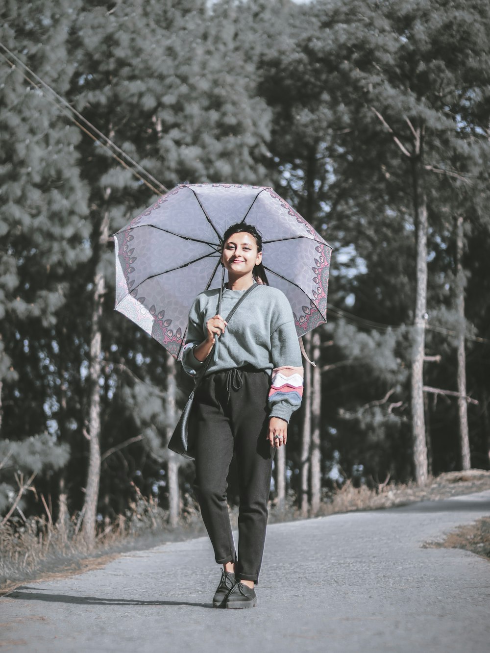 woman walking on road holding umbrella