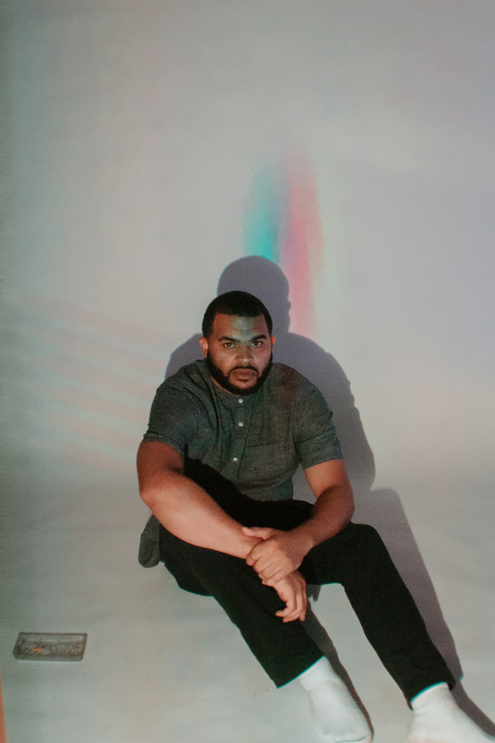 man sitting in front of white wall