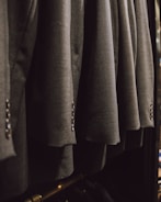a bunch of suits hanging on a rack
