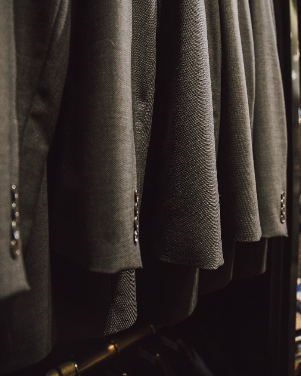 a bunch of suits hanging on a rack