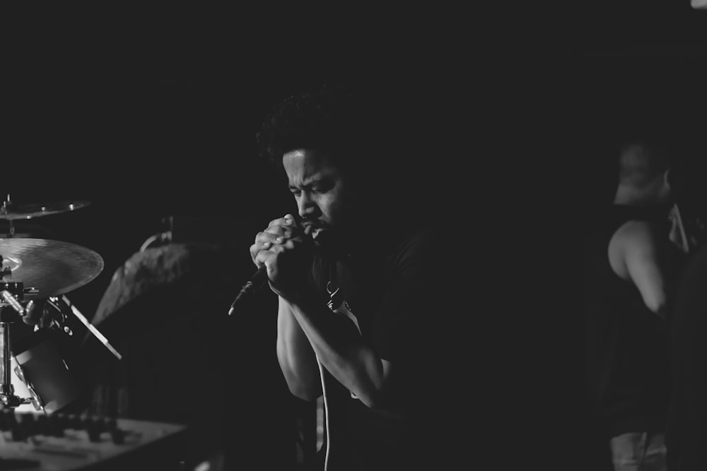 grayscale photography of man holding microphone