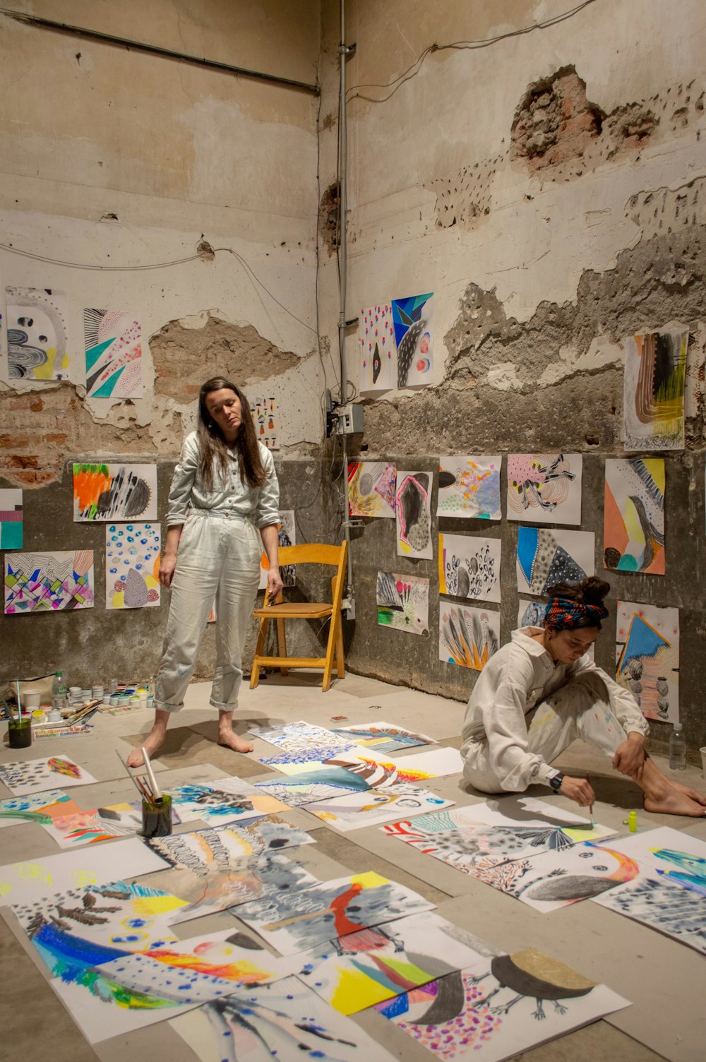 woman standing and another woman sitting on floor