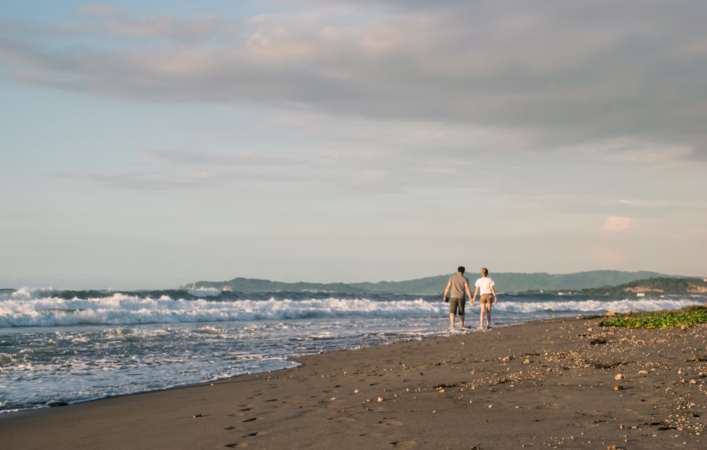 man and woman walking on shore