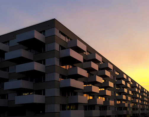 Exterior view of a sleek black and gold accented luxury apartment building at sunset