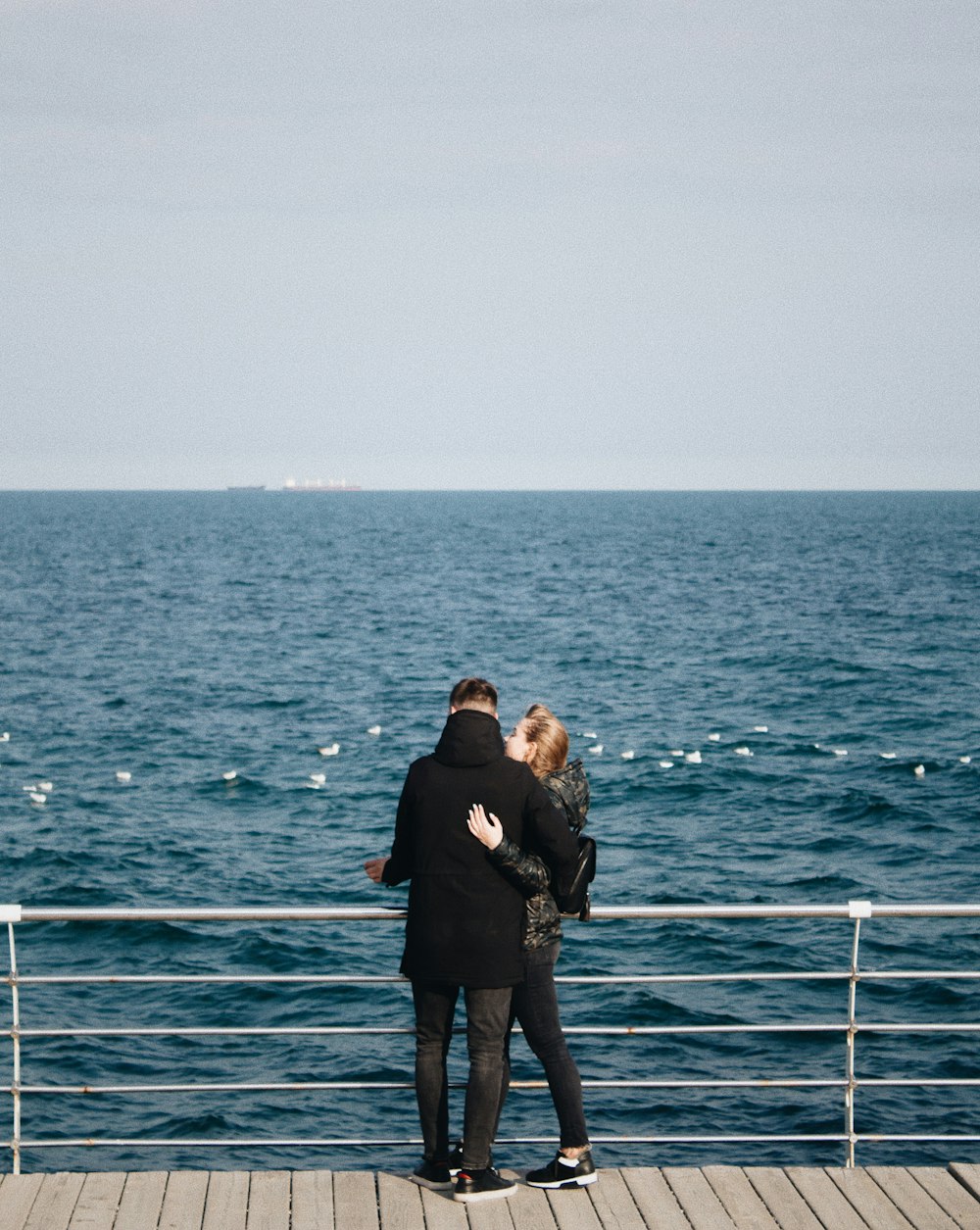 man and woman standing in front of body of water