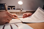 A close-up of hands signing a legal document on a desk.