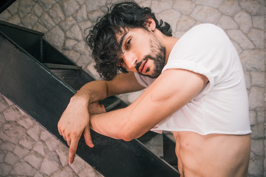 man wearing white crop top standing beside stair