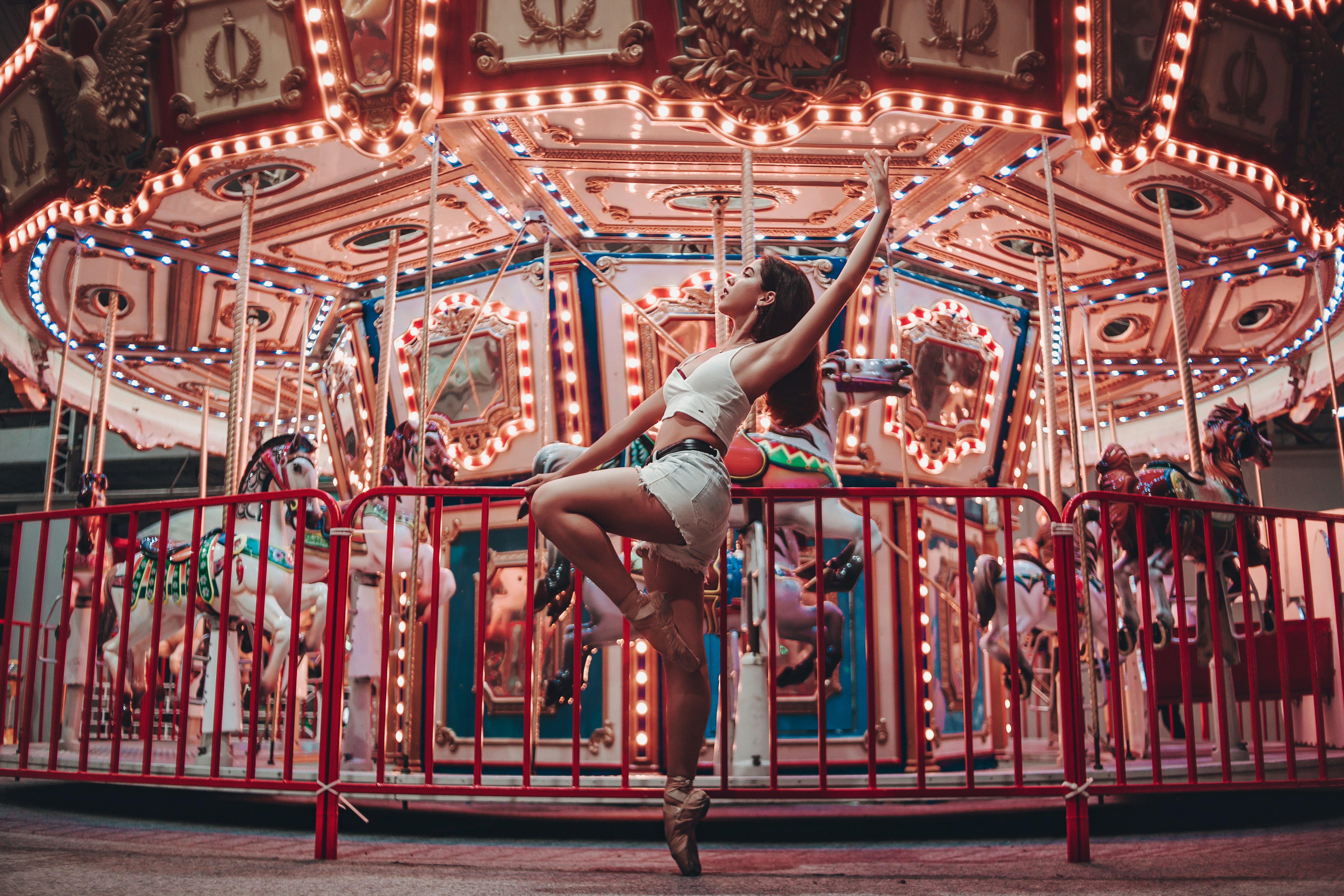 woman sitting on metal rails by turned on merry-go-roudn