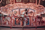 woman sitting on metal rails by turned on merry-go-roudn