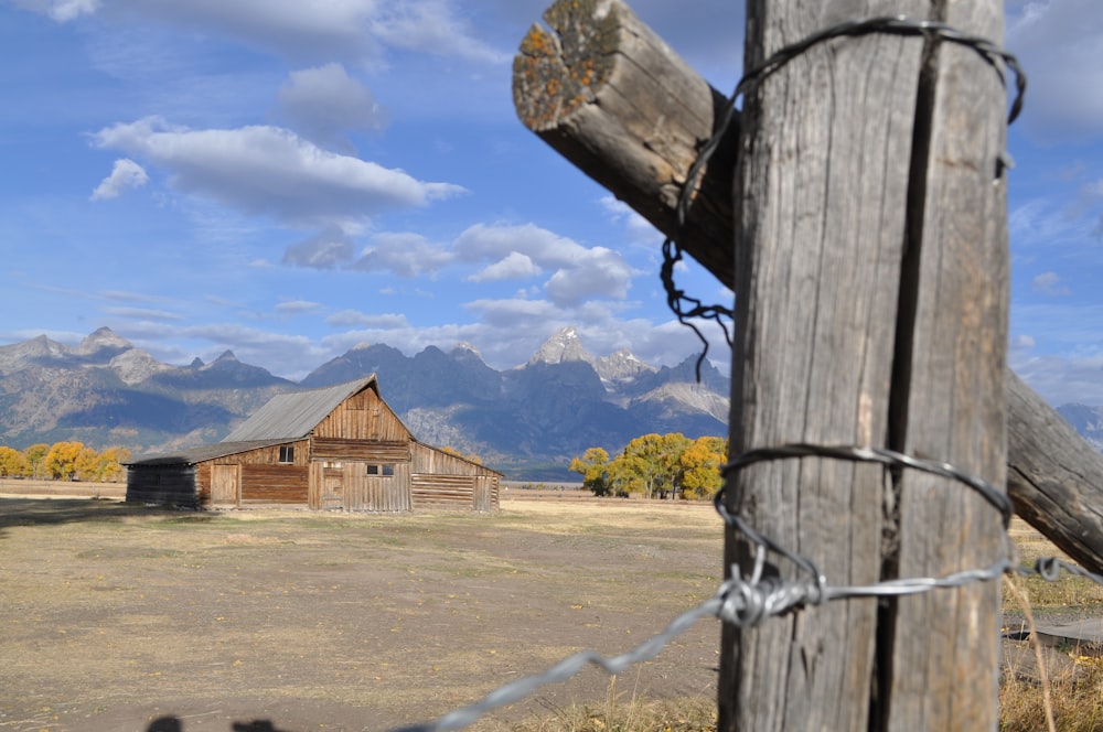 une grange dans un champ avec des montagnes en arrière-plan