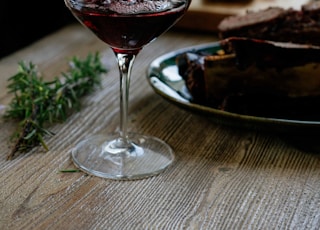 person pouring red wine on wine glass