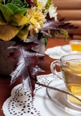 A close-up of a steaming cup of tea with floral decorations.