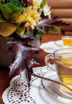 A close-up of a steaming cup of tea with floral decorations.